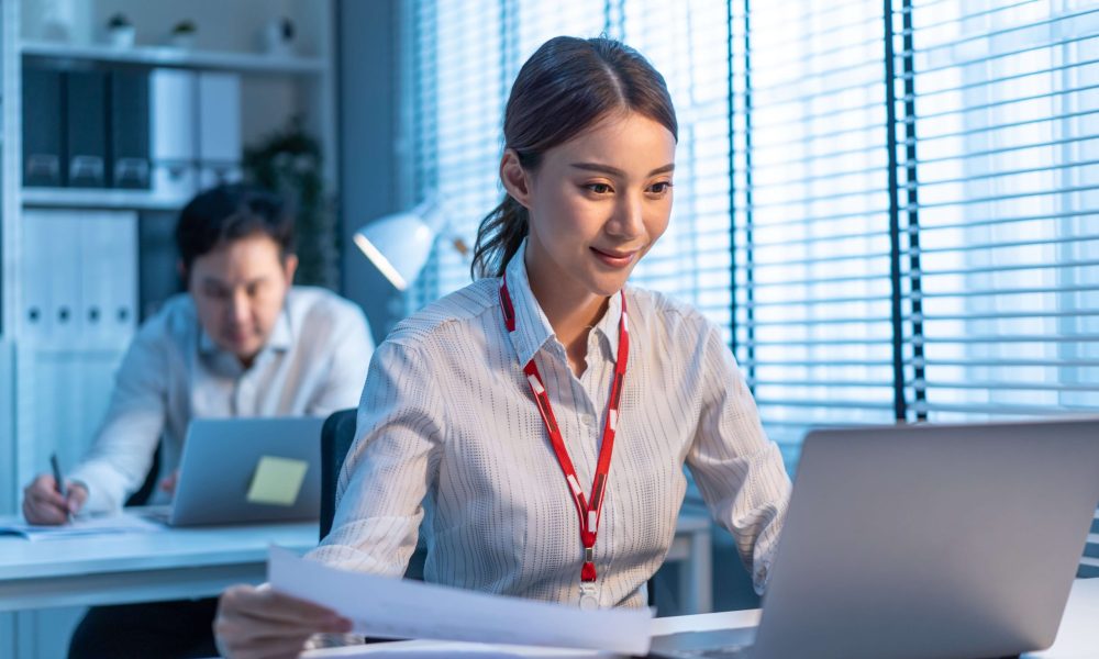 Asian attractive business people overworking late in office workplace. businessman and woman employee worker sitting on table and use laptop computer work and planing for company project of corperate.